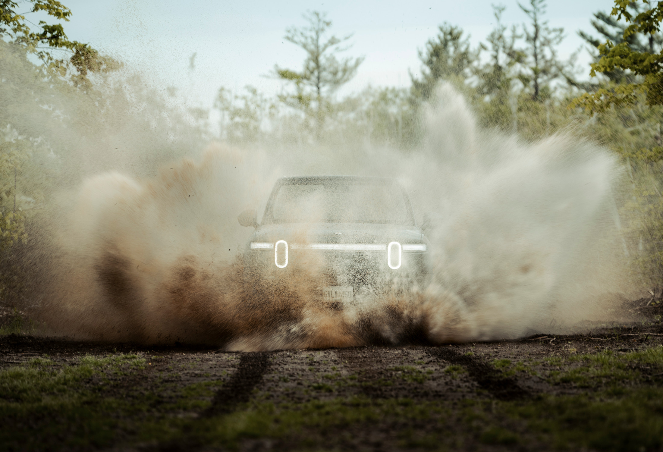 Rivian R1T bursting through mud